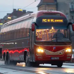 Czerwony autobus PKS Włocławek na mokrej ulicy, idealny do zakupu biletów miesięcznych.