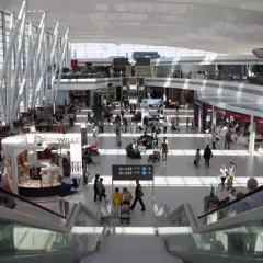 Tętniący życiem terminal lotniska w Budapeszcie, z ludźmi poruszającymi się po sklepach i kawiarniach, gotowi na transport z lotniska.