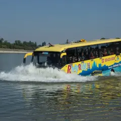 Żółty autobus do Budapesztu, River Ride, wjeżdża do wody, tworząc fale.