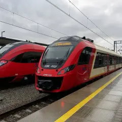 Dwa czerwone pociągi SKM stoją na stacji. Jeden z nich ma na wyświetlaczu informację "SKM Trasa Skrócona", sugerując przebookowanie.