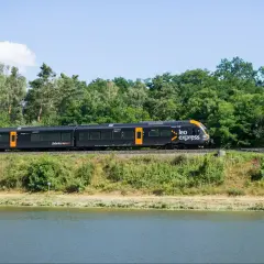 Czarny pociąg Leo Express jedzie wzdłuż zielonego brzegu. Zastanawiasz się, ile kosztuje bilet z Warszawy do Krakowa?