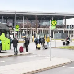 Ludzie z bagażami wsiadają do zielonego autokaru na przystanku autobusowym w Wiedniu Erdberg.