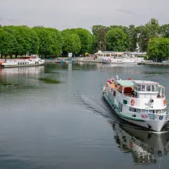 Rejs statkiem po jeziorze w Giżycku, z widokiem na port i zielone drzewa. Podróż z Giżycka do Olsztyna to wspaniała przygoda.