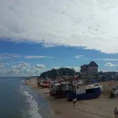 Chłopy atrakcje: łodzie rybackie na plaży, morze i budynki w tle.