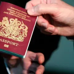 Dłoń trzyma paszport Wielkiej Brytanii. Wkrótce podróż do Norwegii w ramach strefy Schengen.