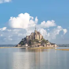Majestatyczny Le Mont Saint-Michel, średniowieczny klasztor na skalistej wyspie, wznosi się nad spokojną wodą.