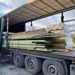 Ładunek drewna i materiałów budowlanych gotowy do eksportu do Niemiec. Na naczepie piętrzą się deski, płyty i rolki wełny mineralnej.