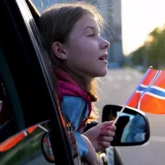 Dziewczynka z flagą Norwegii w ręku, wyjeżdżając samochodem, może symbolizować rejestrację samochodu z Norwegii.