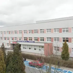 Szpital Miejski im. J. Strusia w Poznaniu. Szukasz informacji, jak dojechać do szpitala na Szwajcarskiej w Poznaniu? Budynek z wieloma oknami, przed którym rosną drzewa.