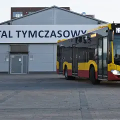 Żółto-czerwony autobus MPK z napisem "W SŁUŻBIE DLA ZDROWIA" dojeżdża do Szpitala Tymczasowego we Wrocławiu przy ul. Borowskiej.