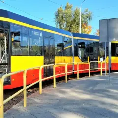 Nowe, nowoczesne grudziądz tramwaje w żółto-czerwonych barwach stoją na torach obok chodnika.