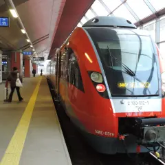 Czerwony pociąg na stacji, gotowy do odjazdu. Sprawdzam rozkład jazdy, by wybrać najlepszą taryfę małopolską.