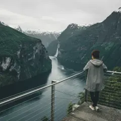 Widok na fiordy w Norwegii. Kobieta podziwia majestatyczne góry i wodę.