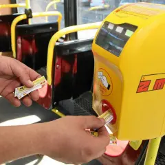 Ręka zbliża bilet do kasownika w autobusie. To prosty sposób, jak dojechać warszawa ztm.