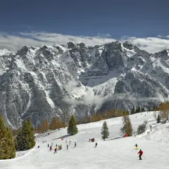Narciarze szusują po ośnieżonych stokach w Marilleva, pod majestatycznymi, skalistymi szczytami Dolomitów.