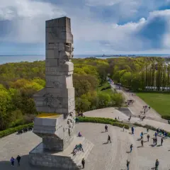 Westerplatte zwiedzanie: monumentalny Pomnik Obrońców Wybrzeża i spacerujący turyści na tle zieleni i morza.