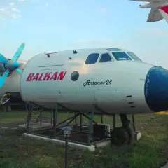 Antonov 24 z napisem BALKAN, jeden z samolotów na bułgarskich lotniskach, stoi na trawie obok ścieżki.