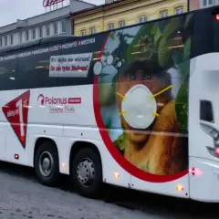 Autobus Neobus z reklamą "bilety od 1 zł" i małpą w masce. Promocja na transport na lotnisko Balice i Chopina.