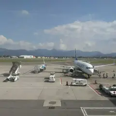 Samolot Ryanair na lotnisku Orio al Serio, pasażerowie wsiadają. W tle góry i chmury.