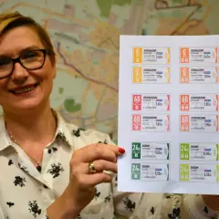 Kobieta prezentuje wydrukowane bilety ZTM Kielce. Na kartce widać różne rodzaje biletów jednorazowych, godzinnych i dobowych, z podanym cennikiem.