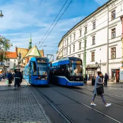 Kraków: dwa niebieskie tramwaje na ulicy, ludzie czekają na przystanku. Idealne na bilet godzinny Kraków.