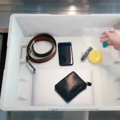 Co wykrywają papierki na lotnisku? Na taśmie leżą: laptop, portfel, telefon, pasek, kosmetyczka z płynami i inne drobiazgi.