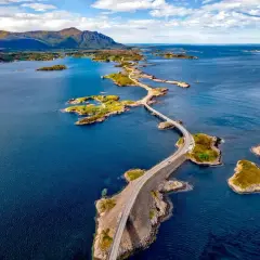 Malownicza droga wijąca się między zielonymi wyspami na tle gór. Norwegia wyspy zachwycają.
