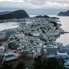 Widok na malownicze miasta w Norwegii, z charakterystyczną architekturą i portem, otoczone wodą i górami.