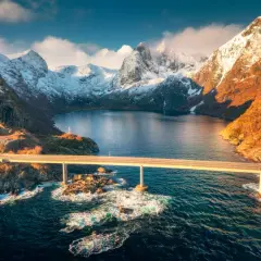 Mosty łączące wyspy w fiordach Norwegii, z ośnieżonymi górami w tle i turkusową wodą.