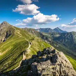 Widok z Rzeszowa na góry Tatry, gdzie szlak turystyczny wije się po zielonych zboczach, prowadząc w stronę Zakopanego.