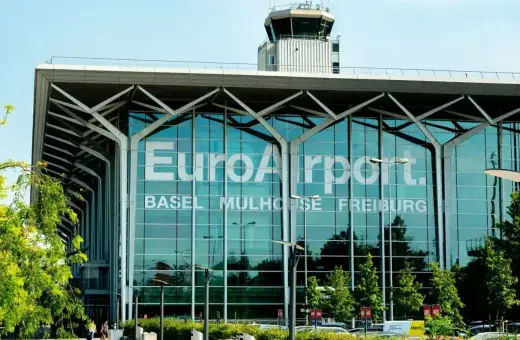 Nowoczesny budynek EuroAirport Basel Mulhouse Freiburg. Szklana fasada z napisem lotniska i wieża kontroli lotów.
