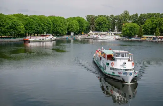 Rejs statkiem po jeziorze w Giżycku, z widokiem na port i zielone drzewa. Podróż z Giżycka do Olsztyna to wspaniała przygoda.