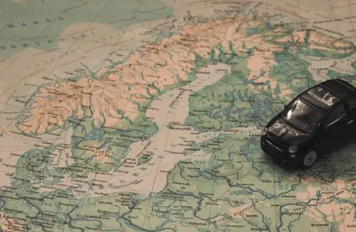 Czarny samochodzik na mapie Europy, wskazujący trasę z Warszawy na Mikołajki.