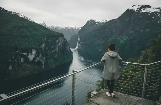 Widok na fiordy w Norwegii. Kobieta podziwia majestatyczne góry i wodę.