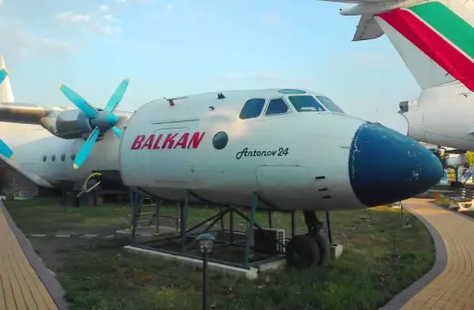 Antonov 24 z napisem BALKAN, jeden z samolotów na bułgarskich lotniskach, stoi na trawie obok ścieżki.