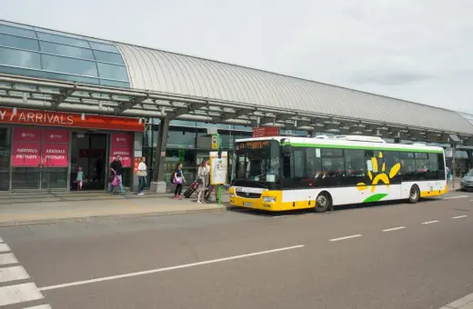 Autobus z logo Modlin Airport czeka na pasażerów przy terminalu.