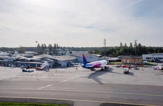 Samolot Wizz Air na płycie lotniska Sztokholm Skavsta. W tle budynki terminali i wieża kontroli lotów.