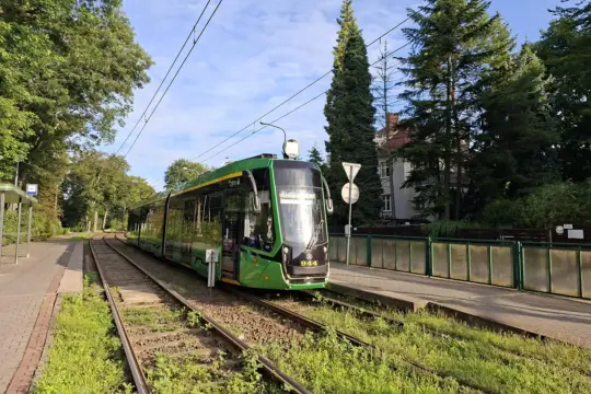 Zielony tramwaj nr 944 na torach, obok przystanku. Sprawdzam l11 rozkład jazdy.