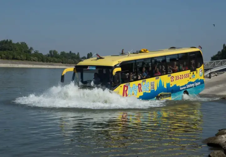 Żółty autobus do Budapesztu, River Ride, wjeżdża do wody, tworząc fale.