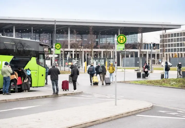 Ludzie z bagażami wsiadają do zielonego autokaru na przystanku autobusowym w Wiedniu Erdberg.