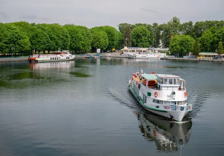 Rejs statkiem po jeziorze w Giżycku, z widokiem na port i zielone drzewa. Podróż z Giżycka do Olsztyna to wspaniała przygoda.