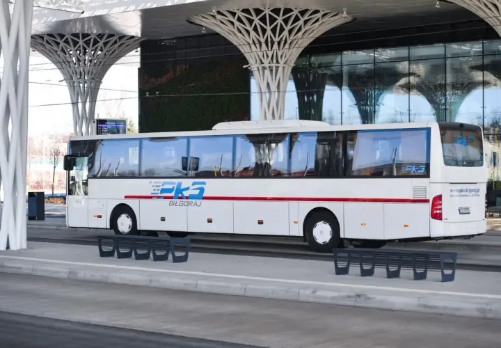 Biały autobus PKS Biłgoraj na nowoczesnym dworcu autobusowym z zieloną ścianą i futurystycznym zadaszeniem.