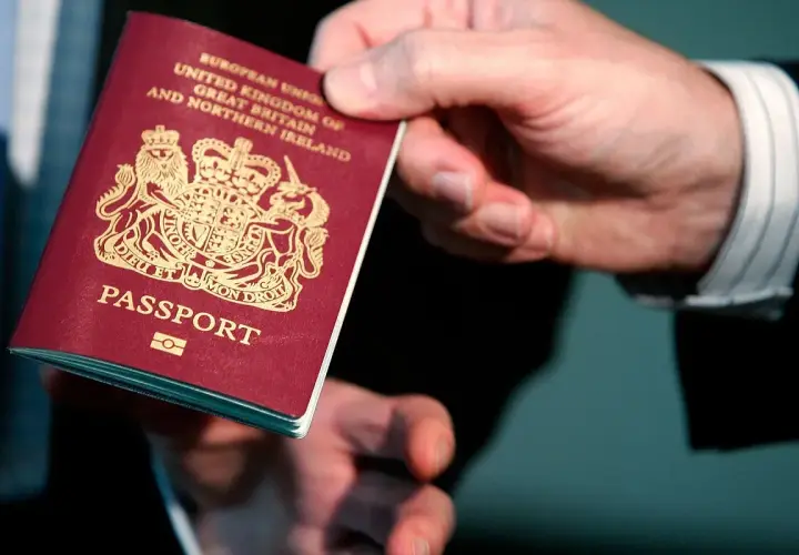 Dłoń trzyma paszport Wielkiej Brytanii. Wkrótce podróż do Norwegii w ramach strefy Schengen.