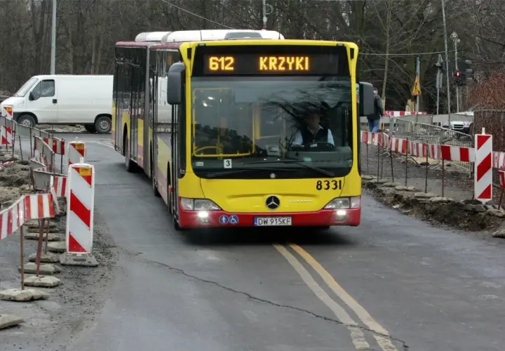 Autobus MPK linii 612 z napisem "KRZYKI" jedzie po drodze z robotami drogowymi. Jak dojechać na Bielany Wrocławskie MPK? Ten autobus może być odpowiedzią.