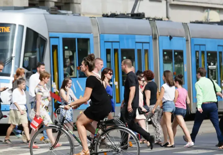 Ludzie przechodzą przez pasy, obok tramwaju z napisem "79 POŚWIETNE". To typowy widok wrocławskiego kod boczny pojazdu.