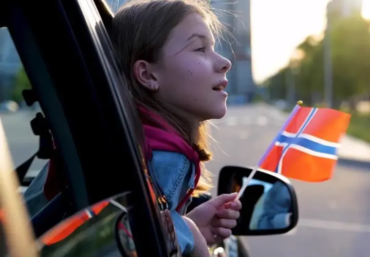 Dziewczynka z flagą Norwegii w ręku, wyjeżdżając samochodem, może symbolizować rejestrację samochodu z Norwegii.