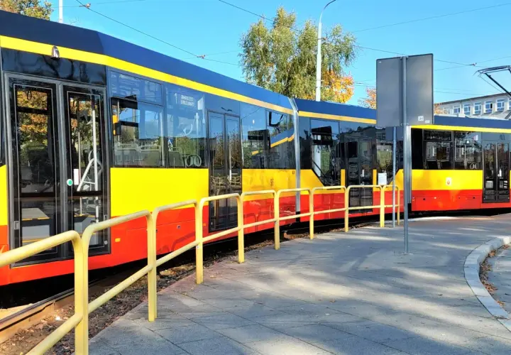 Nowe, nowoczesne grudziądz tramwaje w żółto-czerwonych barwach stoją na torach obok chodnika.