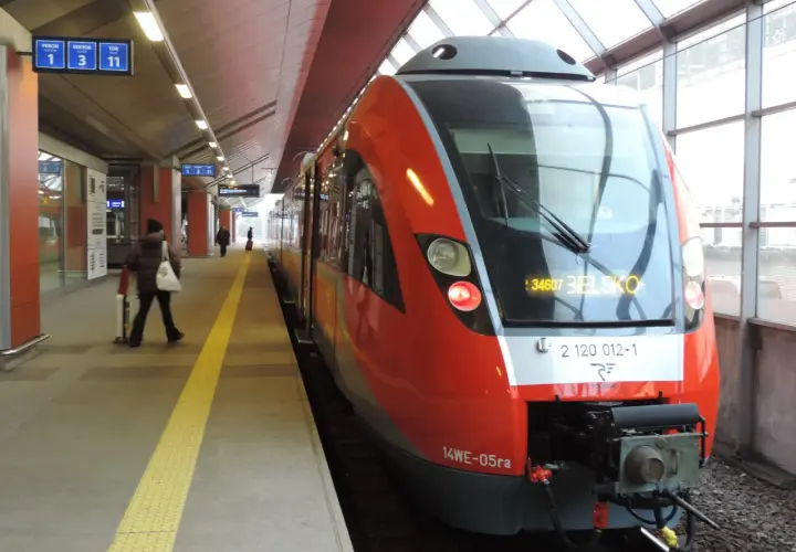 Czerwony pociąg na stacji, gotowy do odjazdu. Sprawdzam rozkład jazdy, by wybrać najlepszą taryfę małopolską.