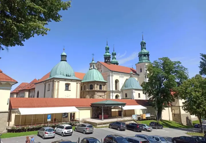 Kraków Kalwaria Zebrzydowska: imponujący zespół klasztorny z zielonymi kopułami i wieżami, otoczony parkingiem i drzewami.