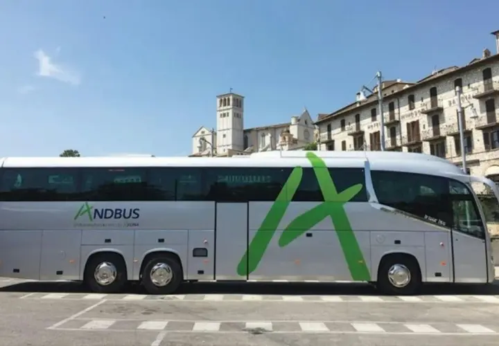 Autokar ANDBUS, idealny na podróż z Barcelony do Andory, parkuje przed zabytkową zabudową.